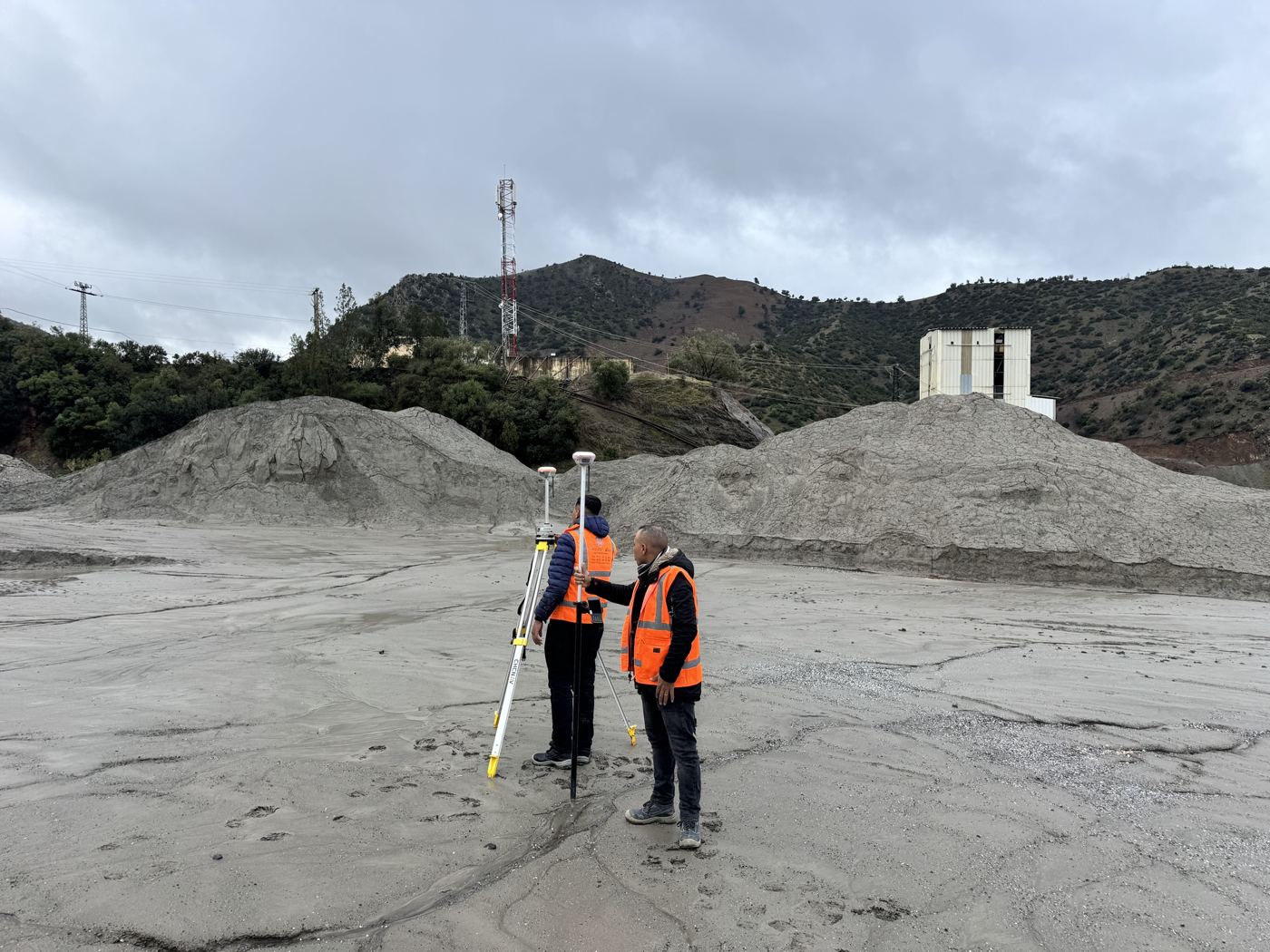 Deux opérateurs installant une base GNSS sur le carreau d'une mine